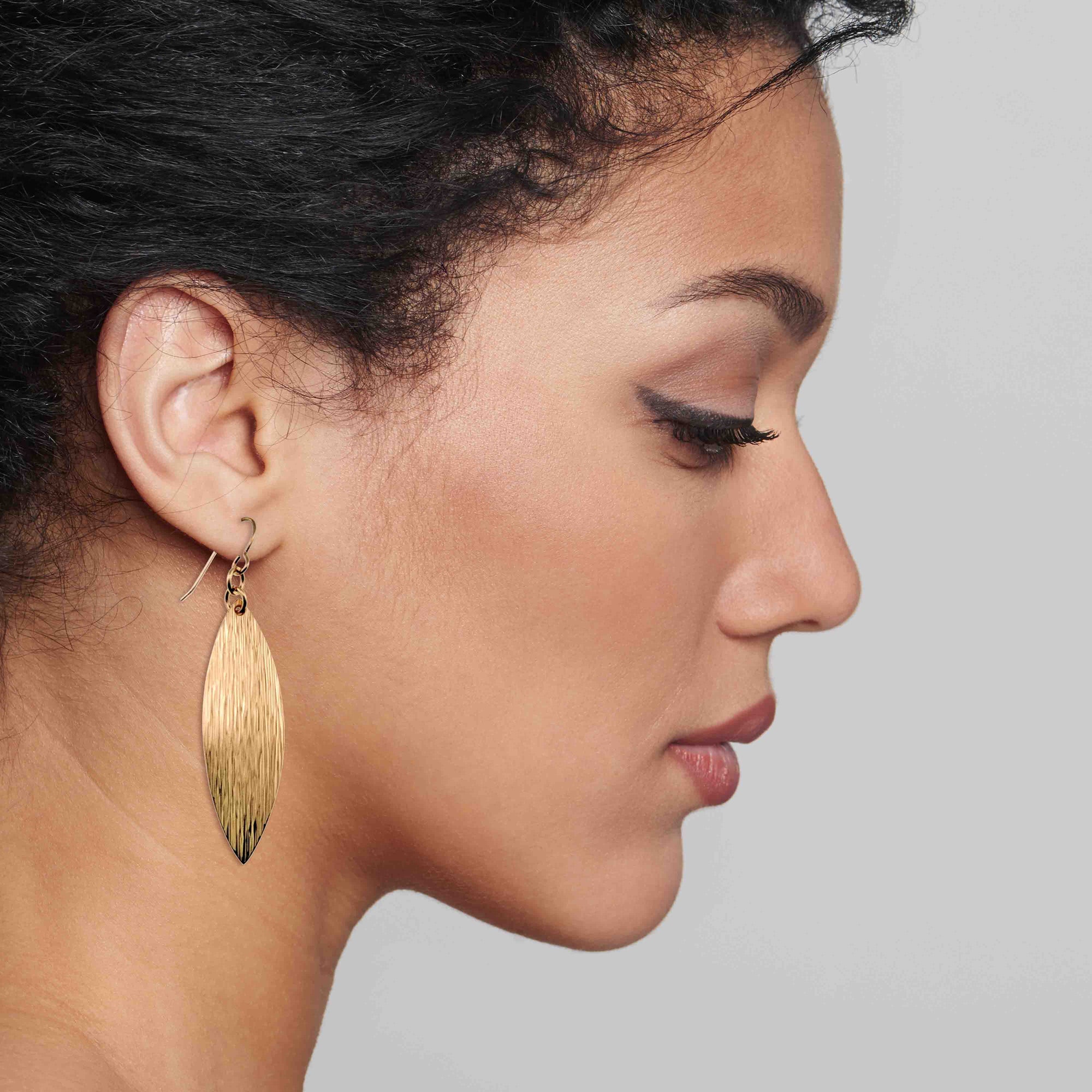 Close-up of a woman wearing Bronze Bark Leaf Drop Earrings against a neutral background
