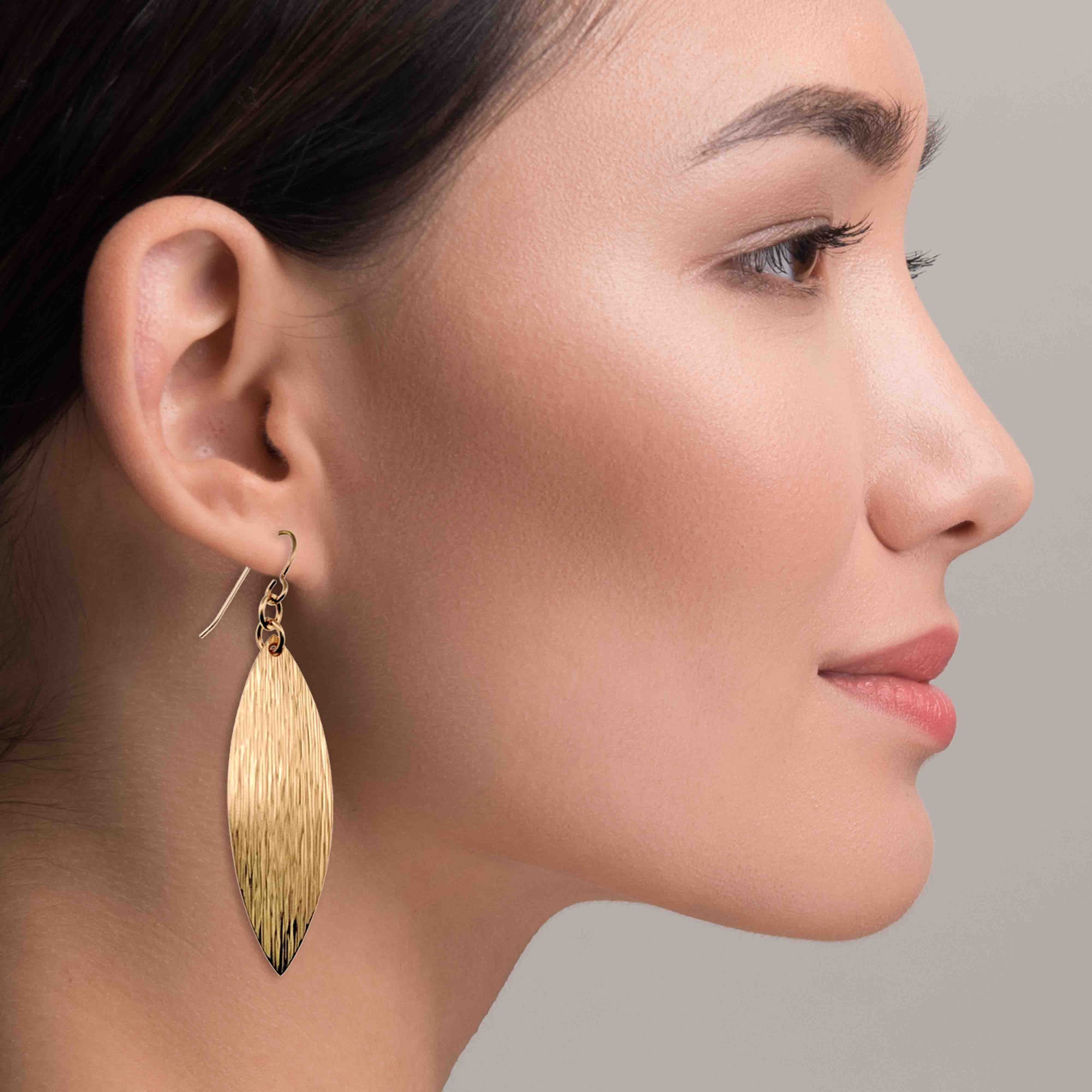 Close-up of a woman wearing Bronze Bark Leaf Drop Earrings against a neutral background