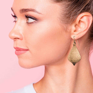 2 of 7: Close-up of a woman wearing Bronze Damask Arabesque Drop Earrings  against a pink background