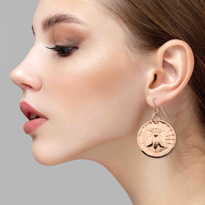 2 of 7: Close-up of a woman wearing Bronze Queen Bee Disc Drop Earrings against a gray background