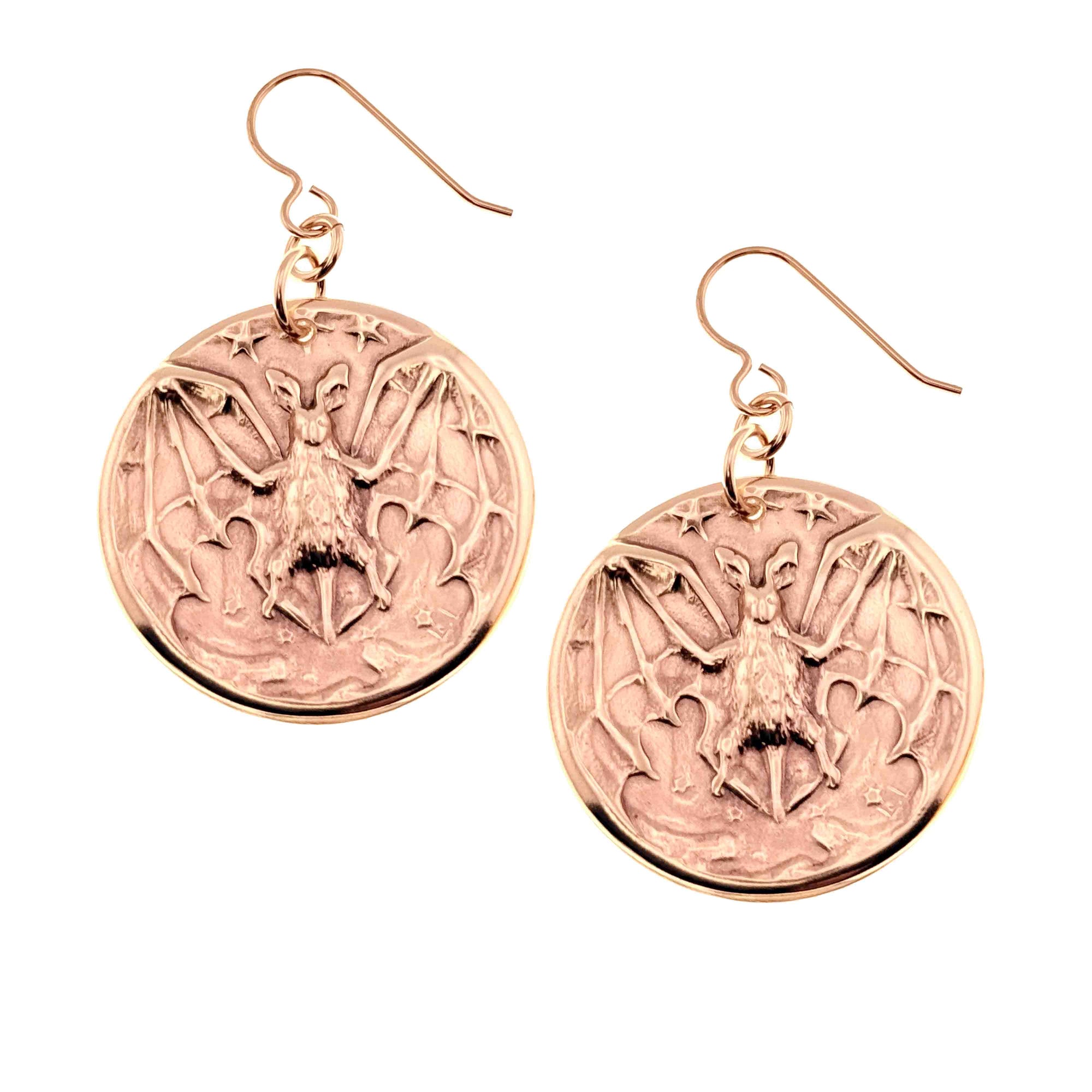 A Pair of Bronze Vampire Bat Disc Dangle Earrings on a White Background