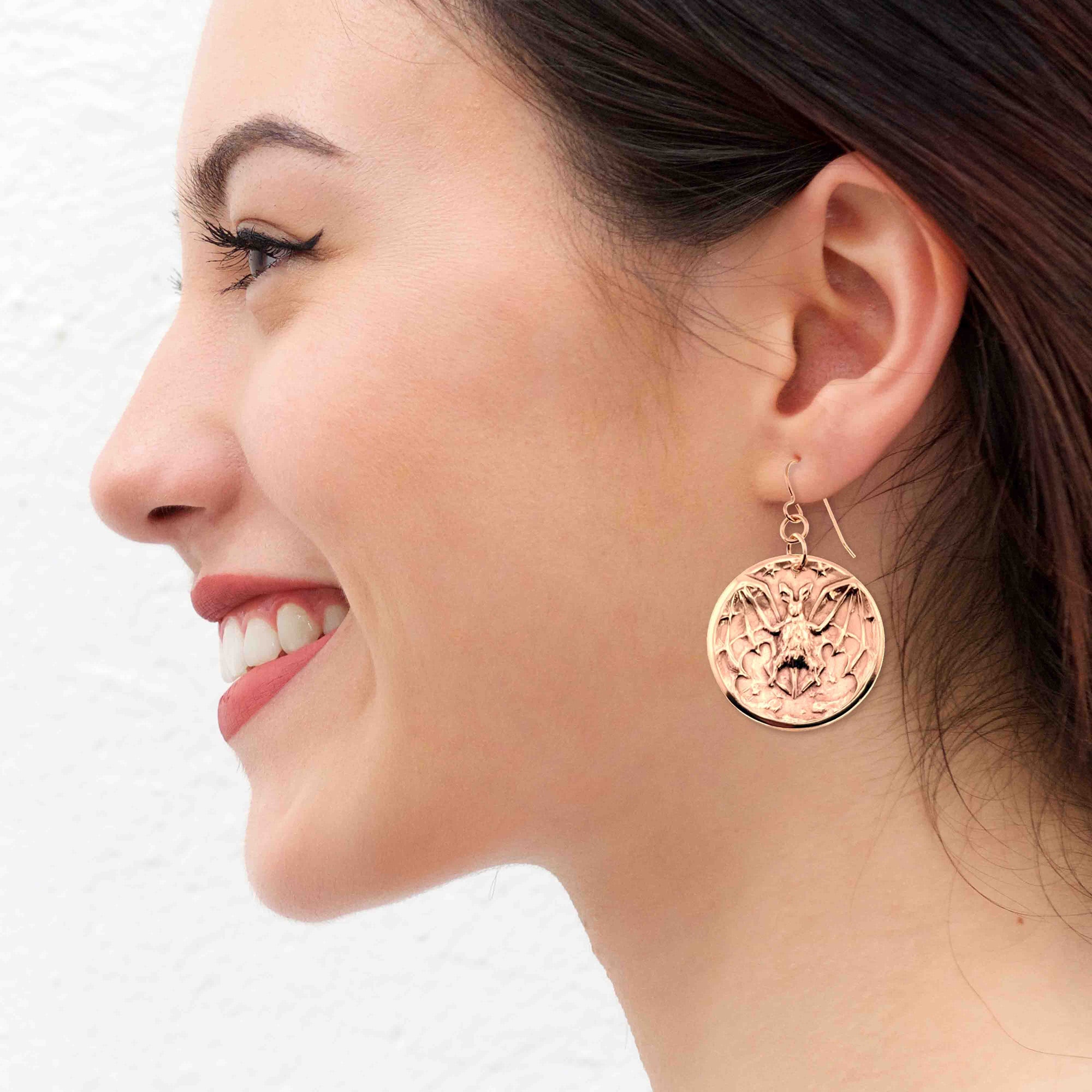 Woman wearing Bronze Vampire Bat Disc Dangle Earrings with a white background