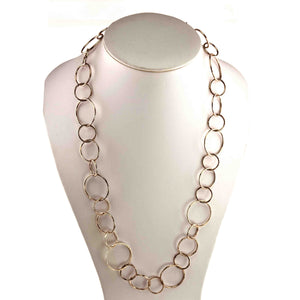 5 of 6: Chased Bronze Link Chain Necklace displayed on a white jewelry bust. The 26 inch necklace features alternating circular and oval bronze links in varied sizes, creating an open airy pattern. Chased texture along the polished link edges adds visible handmade detail.