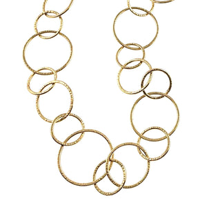 3 of 8: Close view of the Chased Nu Gold Brass Chain Link Necklace showing its varied round and oval links against a white background. The golden Nu Gold brass links display a hand hammered texture around their edges, with larger circles joined by smaller round and elongated links.