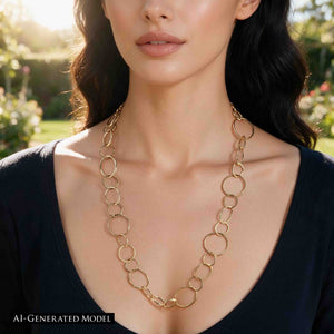 7 of 8: AI Generated Model wearing the Chased Nu Gold Brass Chain Link Necklace with a black scoop neck top outdoors in warm sunlight. The 26 inch golden brass necklace hangs below the collarbone and shows alternating round and oval links in three sizes with a bright hand hammered finish.