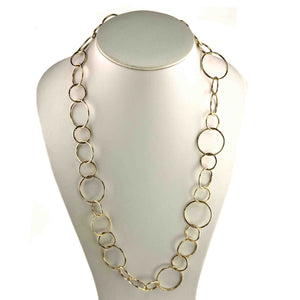 5 of 8: Chased Nu Gold Brass Chain Link Necklace displayed on a white jewelry bust. The long necklace features an open link design with alternating round and oval shapes in three sizes. Warm golden Nu Gold brass and hand hammered surfaces create visible texture across the polished links.