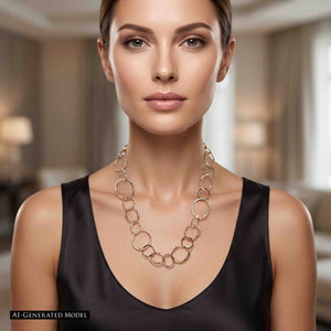 2 of 6: AI generated Woman wearing the Chased Bronze Link Chain Necklace with a black sleeveless scoop neck top. The long bronze necklace features alternating circular and oval links in several sizes, with a warm polished tone and visible chased texture. The 26 inch length falls across the upper chest for a bold statement look.