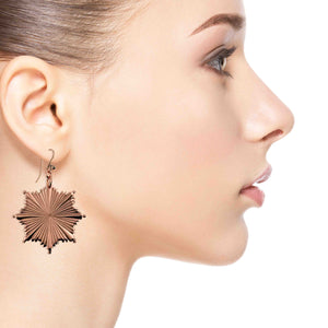 2 of 8: Close-up of a woman wearing a Christmas Starburst Copper Earring on a white background