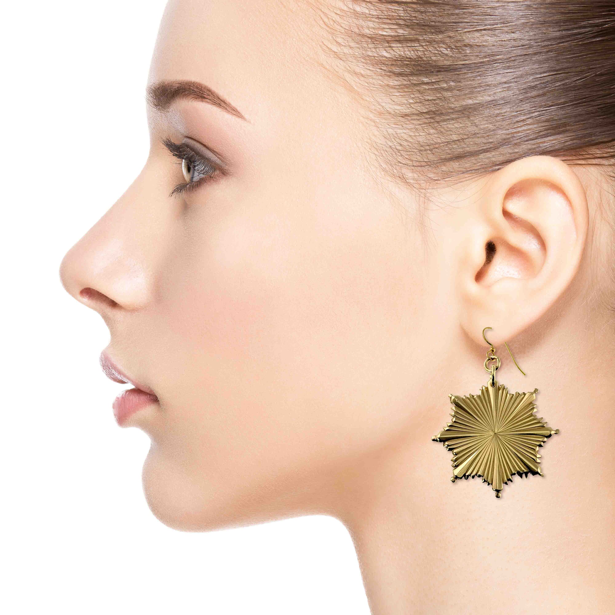 Christmas Starburst Nu Gold Brass Earring worn by a model on a white background