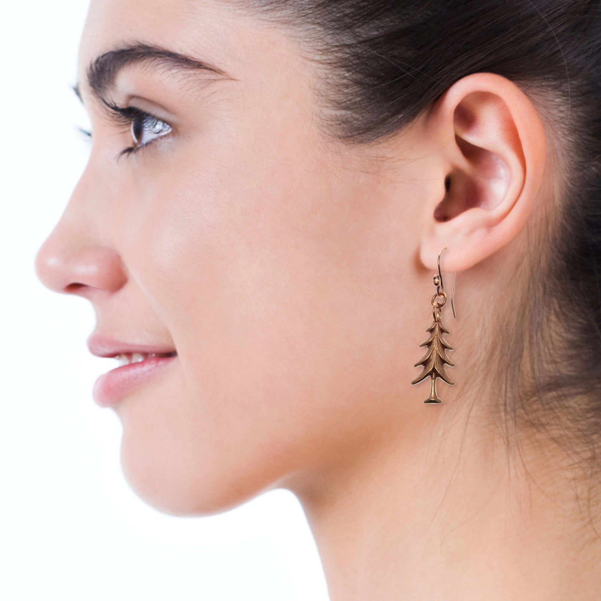 Close up of Christmas Tree Charm Copper Dangle Earrings on a Female Model