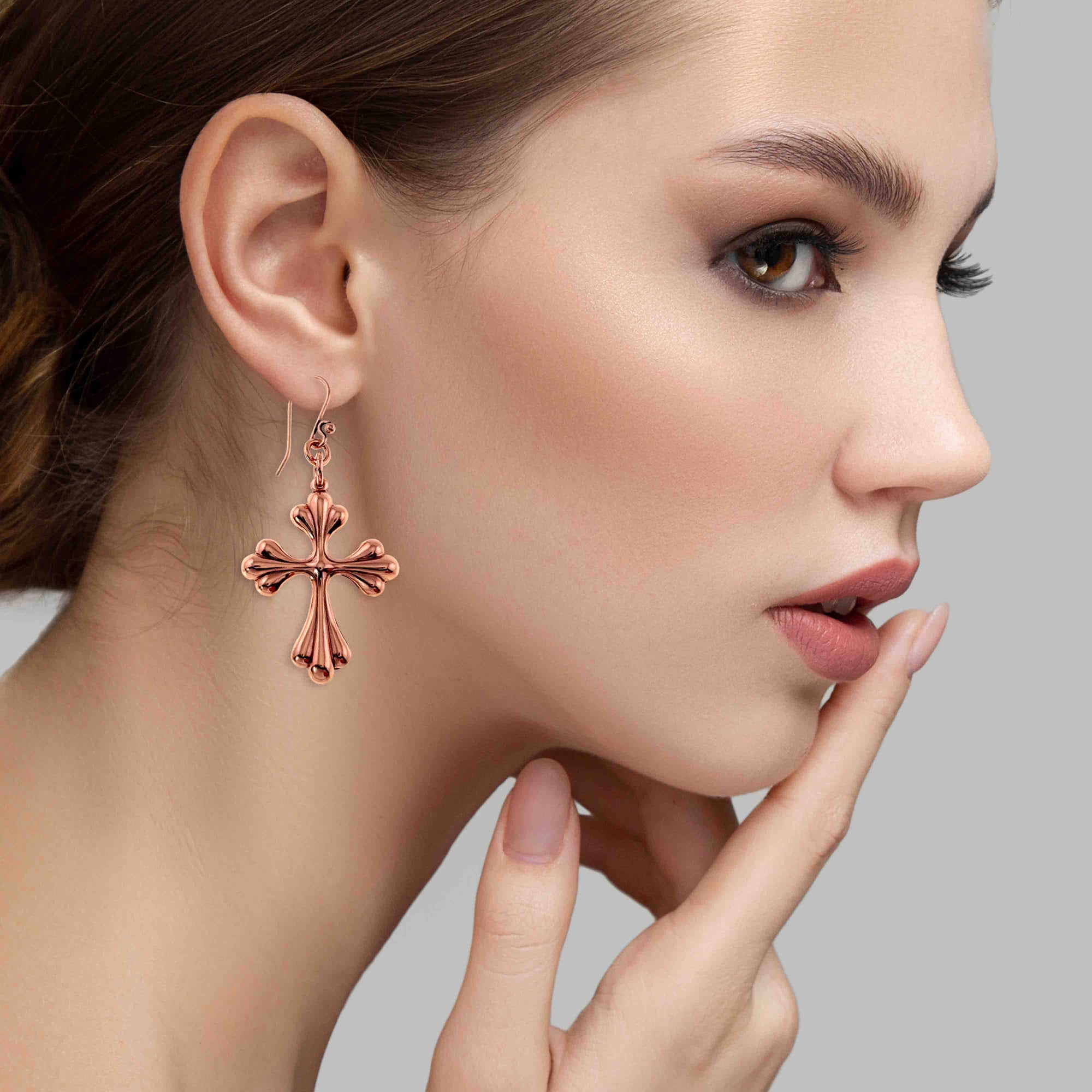 Close-up of a woman wearing a Copper Baroque Cross Drop Earring against a neutral background
