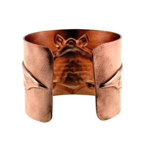 9 of 11: Rear view of the Copper Bat Cuff Bracelet showing the open cuff design, smooth rounded ends, brushed raw copper surface, and the raised bat motif visible through the inside of the bracelet. The wide solid copper cuff is photographed against a white background.