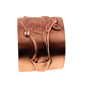 10 of 11: Side view of the Copper Bat Cuff Bracelet showing the raised die struck flying bat design extending across the wide brushed copper cuff. The bat body, ears, wings, and long wing details stand above the warm raw copper surface against a white background.
