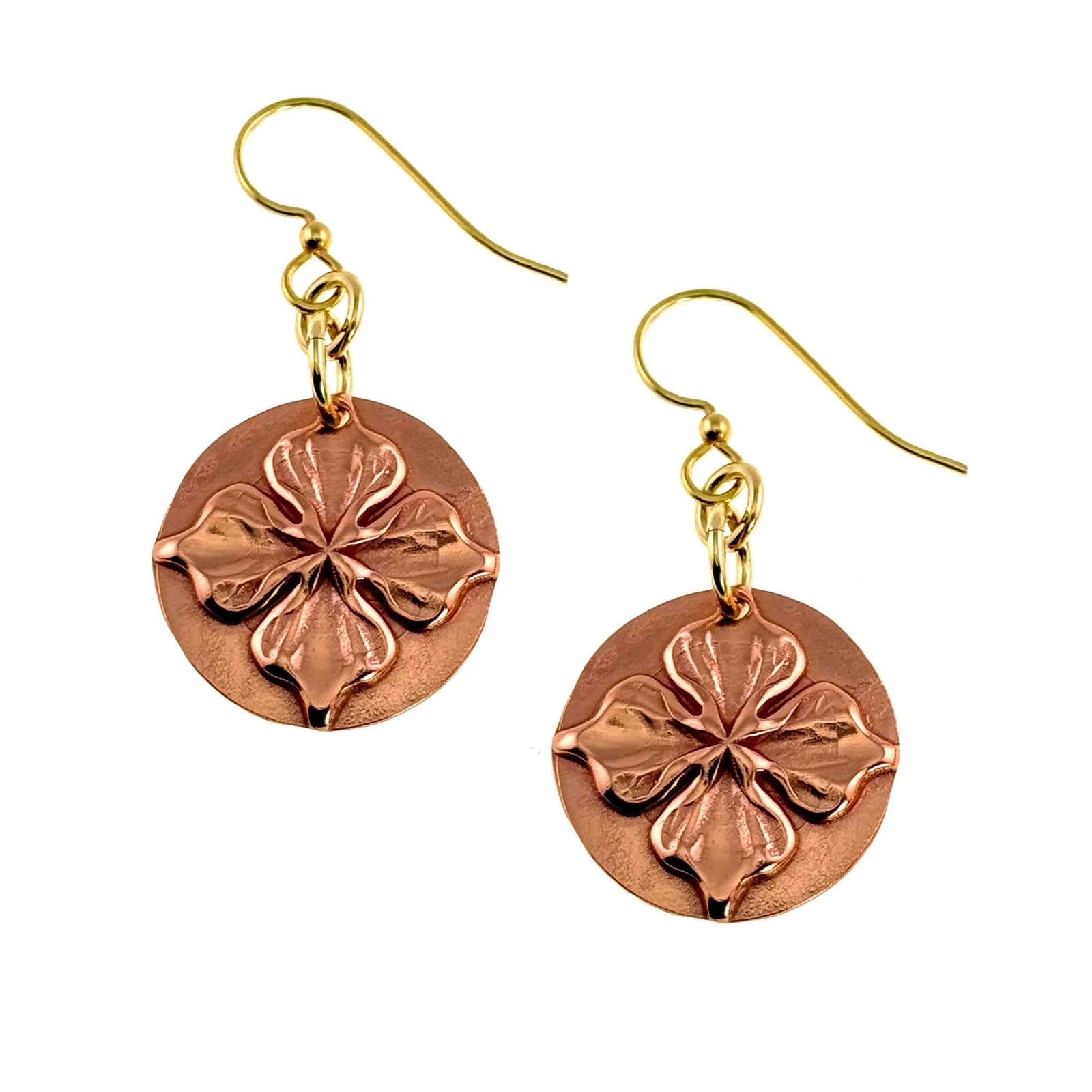 Handcrafted copper disc earrings featuring a raised four petal blossom design in the center. The polished raw copper medallions hang from brass French hook ear wires with small gold tone jump rings. Floral detailing adds depth and texture, creating a warm, glowing finish perfect for spring or everyday wear.