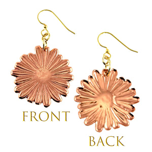 3 of 7: Front and back view of handcrafted copper daisy dangle earrings with detailed petal texture and a polished finish. The front shows radiating lines and a defined floral center, while the back reveals a smooth, slightly concave surface. Each earring hangs from a gold tone brass French hook, displayed on a clean white background.