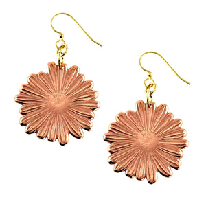 1 of 7: Handcrafted copper daisy dangle earrings with detailed petal texture and a polished finish, suspended from gold tone brass French hooks, shown against a clean white background. Each earring features a round floral shape with radiating lines that catch the light, creating a warm, natural glow.