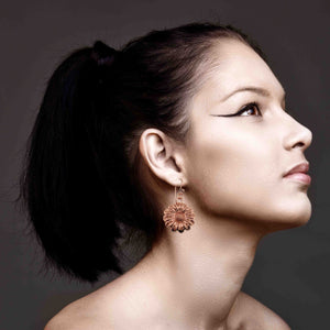7 of 8: Woman wearing Copper Daisy Disc Drop Earrings against a dark background