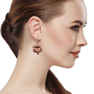 2 of 7: Close-up of a woman wearing a floral earring on a white background