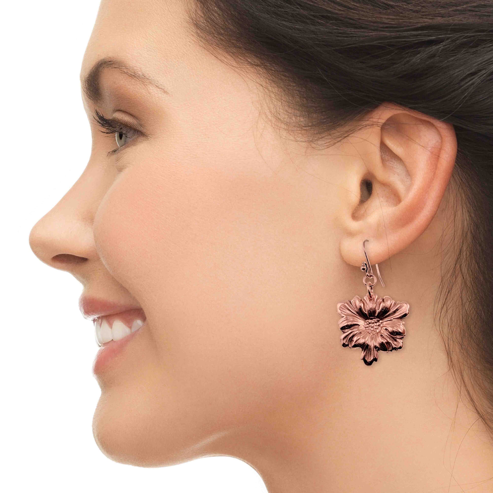 Close-up of a woman wearing Dogwood Blossom Copper Drop Earrings on a white background