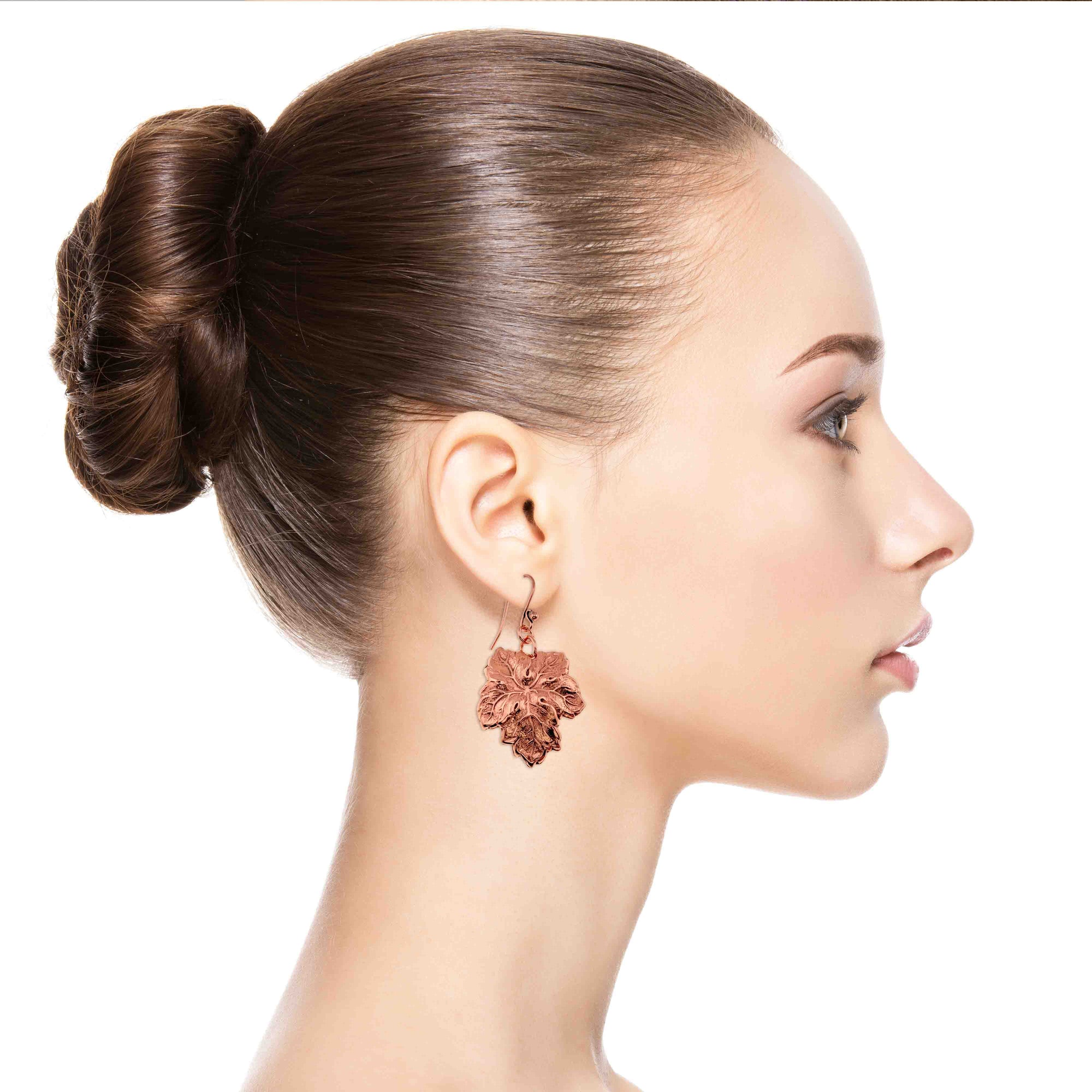 Woman wearing Grape Leaf Copper Dangle Earrings with a plain background