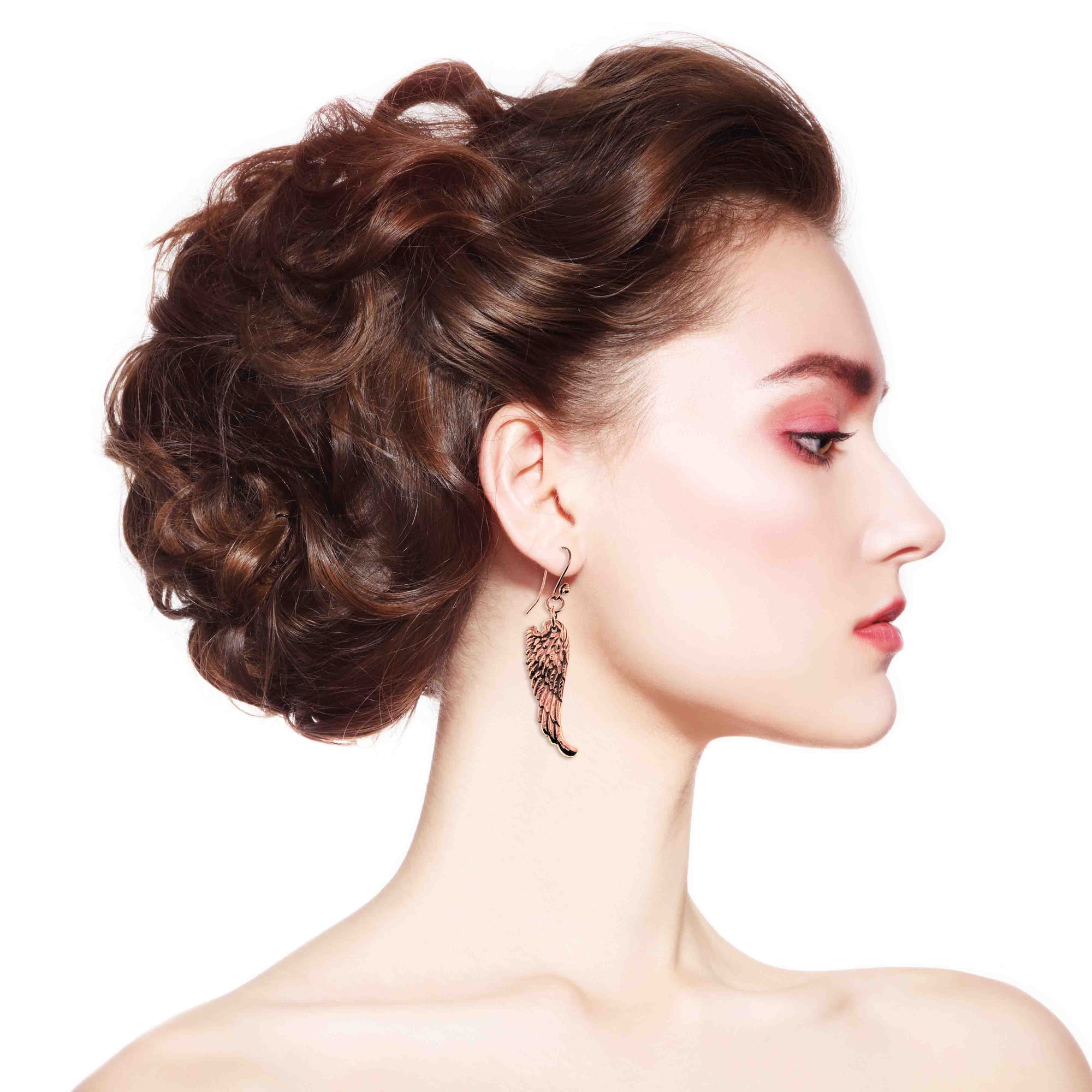 Woman with styled hair and wearing Copper Guardian Angel Wing Drop Earrings on a white background