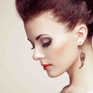 4 of 8: Close-up of a woman's profile with a focus on her Copper Guardian Angel Wing Drop Earrings against a neutral background