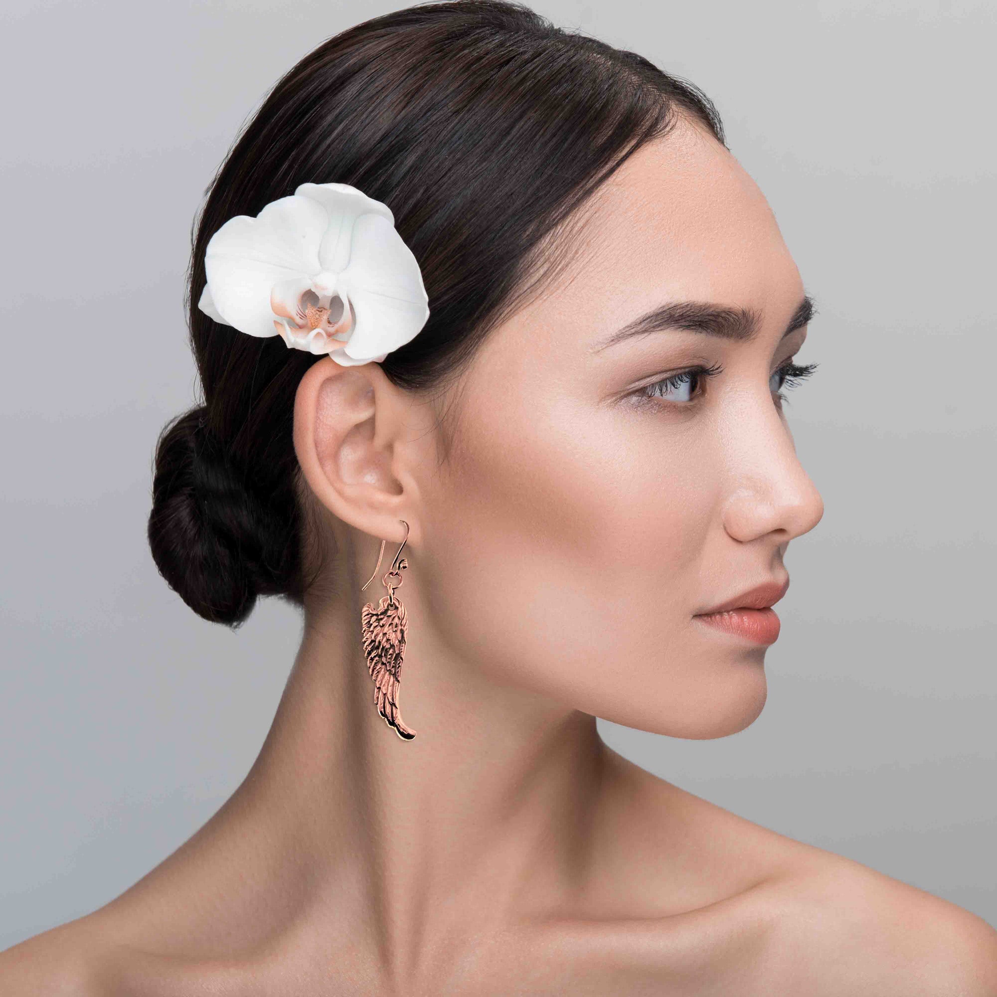 Woman with a white orchid in her hair against a gray background wearing Copper Guardian Angel Wing Drop Earrings
