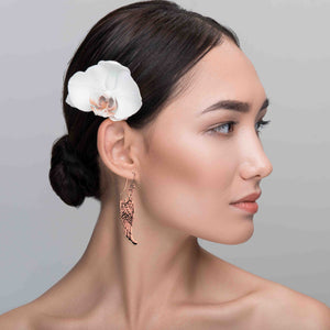 6 of 8: Woman with a white orchid in her hair against a gray background wearing Copper Guardian Angel Wing Drop Earrings