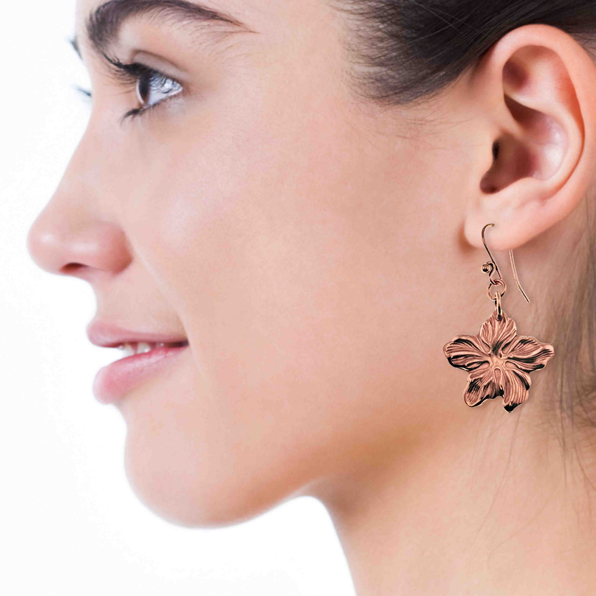 A Smiling Woman Wearing Copper Hibiscus Dangle Earrings