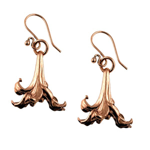1 of 7: A pair of handcrafted copper drop earrings shaped like blooming lily flowers. Each earring features detailed die-struck petals with a soft, flowing design and a warm, polished copper finish. They hang from simple copper French ear wires, creating a natural and elegant look.