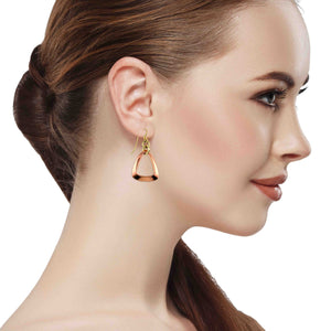 6 of 7: Close up side profile of a woman wearing polished copper open teardrop frame earrings with brass French ear wires. The earrings feature a smooth, rounded triangular open center in raw, non patinated copper with a warm rose gold tone and high shine reflective finish. The lightweight design hangs just below the earlobe, adding a modern, elegant accent against her pulled back hair and soft neutral background.