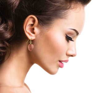 6 of 7: Close-up of a woman wearing a Copper Pine Cone Dangle Earring on a white background
