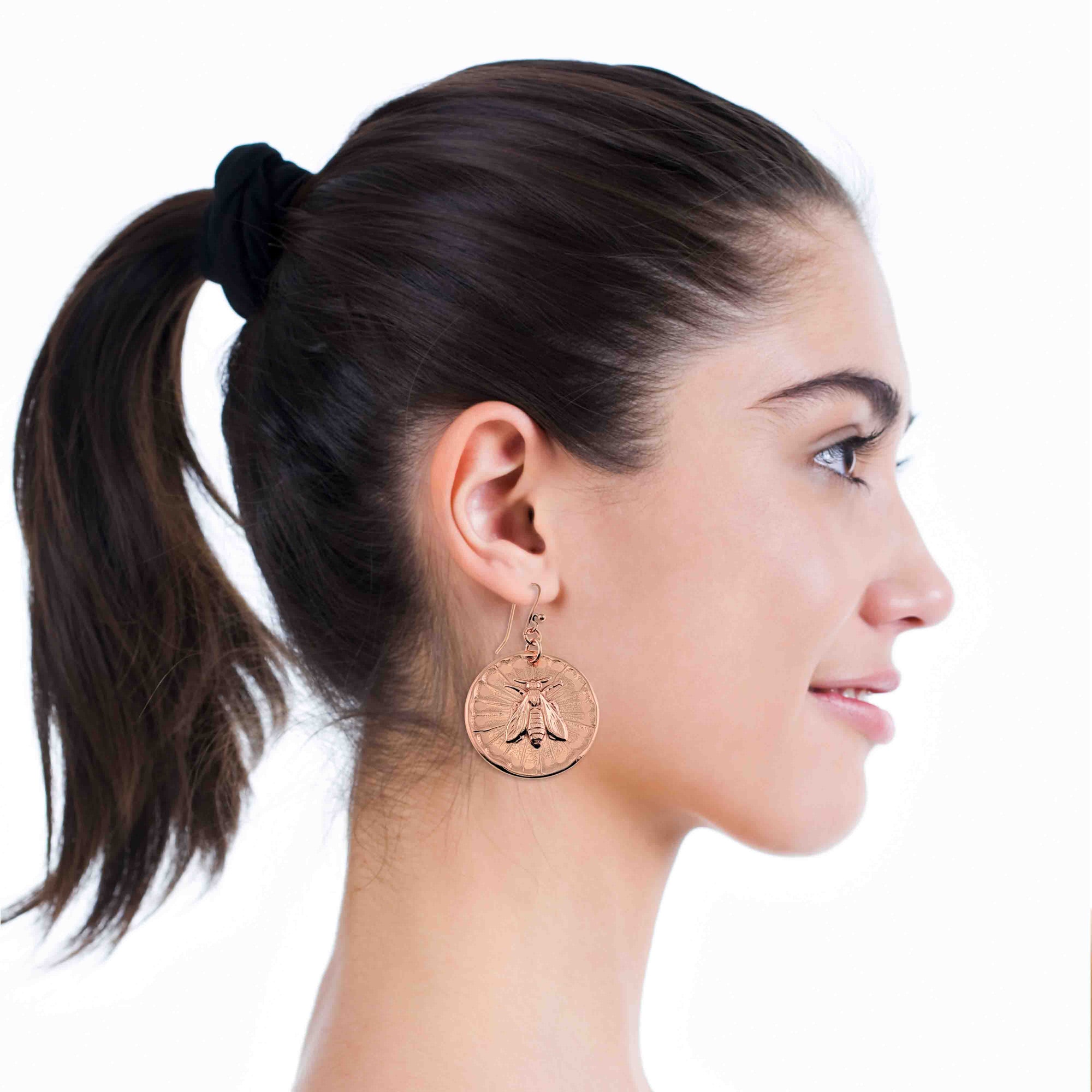 Woman wearing Copper Queen Bee Disc Drop Earrings with a plain background