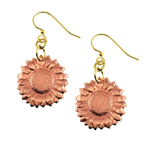 1 of 7: Handcrafted copper sunflower dangle earrings with detailed die struck petals and textured centers. The warm raw copper medallions hang from gold tone brass French ear wires, creating a soft contrast of color. Feminine floral design with a polished finish, lightweight and ideal for everyday wear or spring and summer outfits.