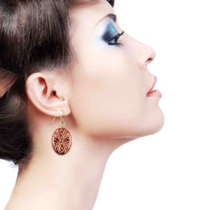 4 of 7: Close-up side profile of a woman wearing a handcrafted copper Victorian oval dangle earring with detailed scrollwork, brass French ear wire, and warm polished finish, highlighting the elegant drop length against her neck and soft makeup with blue eyeshadow on a clean white background.