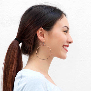 4 of 8: A Smiling Woman Wearing Corrugated Copper Hoop Earrings