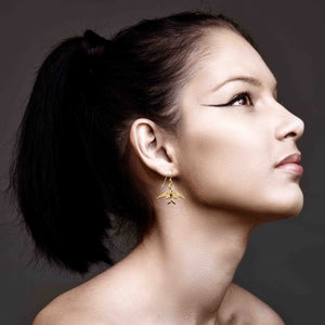 2 of 7: Woman wearing Dainty Nu Gold Brass Swallow Earrings against a dark background