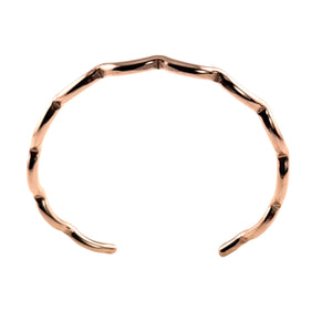 5 of 9: Front view of a slim open cuff bracelet in polished copper on a white background. The bracelet features a narrow band with softly irregular faceted edges and a warm rose copper tone. Its open ends curve slightly outward, while the reflective surface highlights the handcrafted texture and clean modern shape.