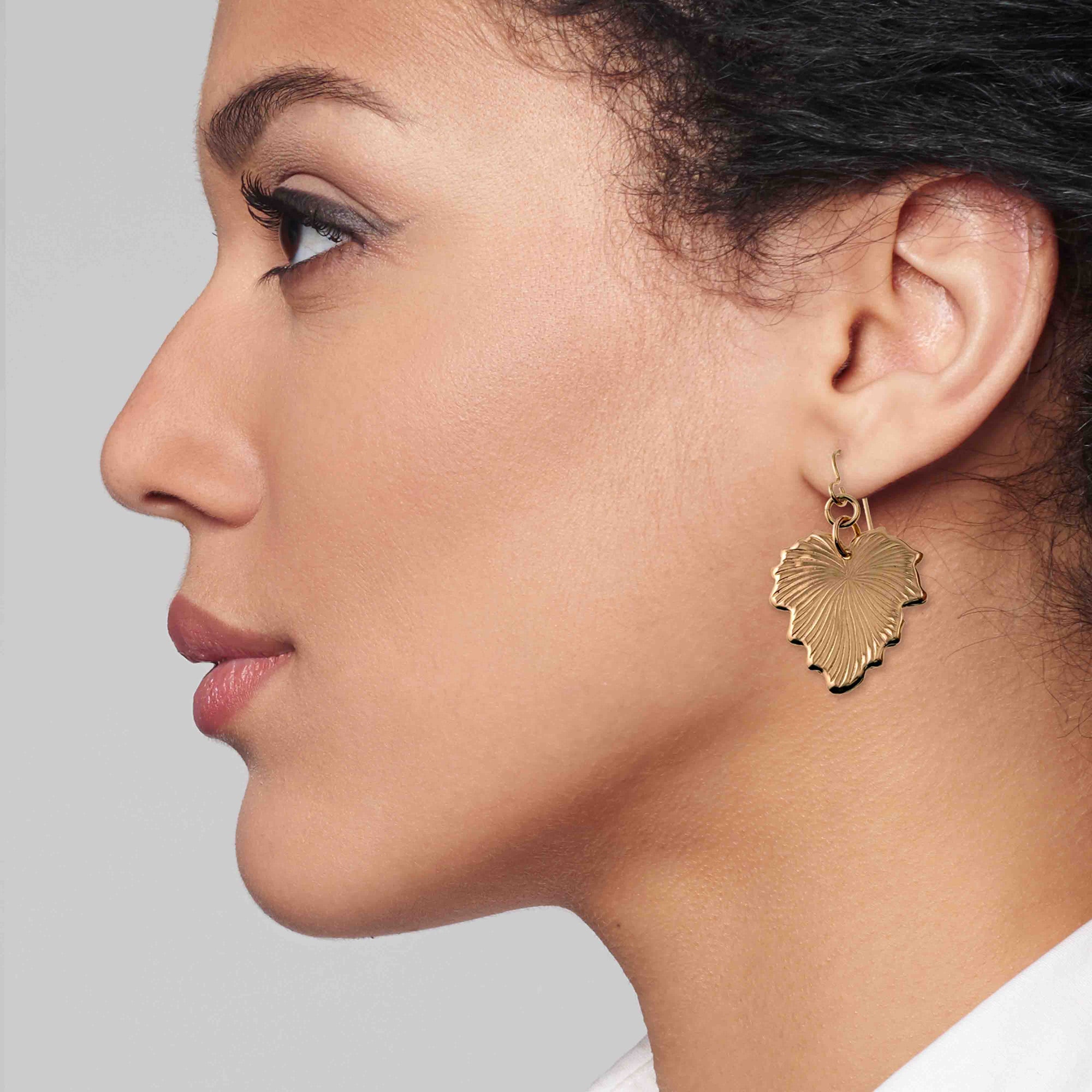 Close-up of a woman wearing a Grape Leaf Bronze Dangle Earring against a neutral background