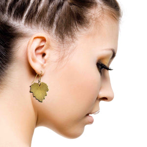 6 of 7: Close-up of a woman wearing Grape Leaf Nu Gold Brass Dangle Earrings on a white background
