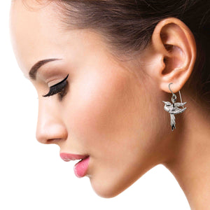 2 of 7: Close-up of a woman wearing an elegant earring on a white background