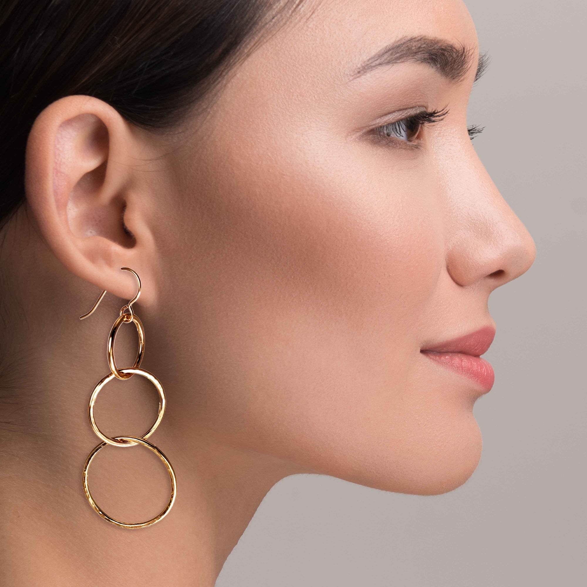 An Elegant Woman Wearing Hammered Bronze Three Tiered Dangle Earrings