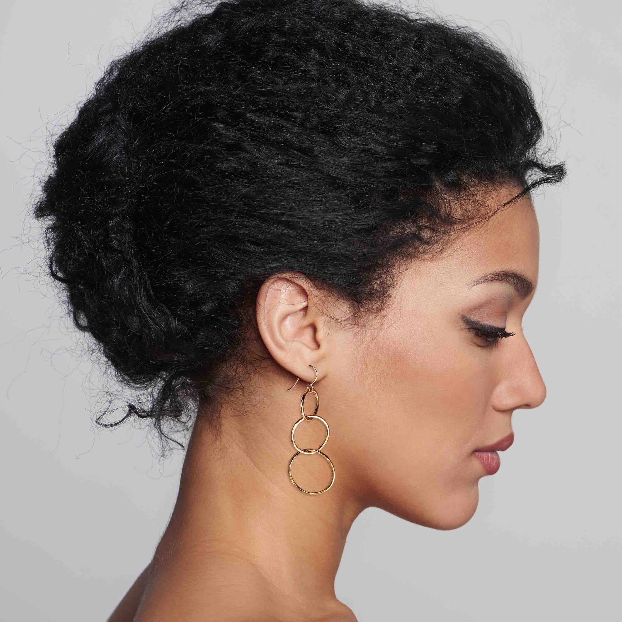 A Chic Woman Wearing Hammered Bronze Three Tiered Dangle Earrings