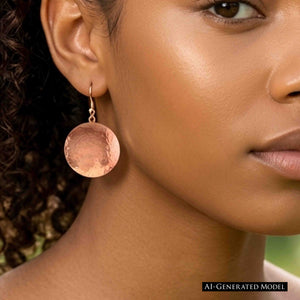 4 of 7: Close view of a woman with curly dark hair and warm brown skin wearing a Hammered Copper Disc Earring outdoors. The polished round copper disc and hammered surface catch the light while hanging below the earlobe. AI generated model image.