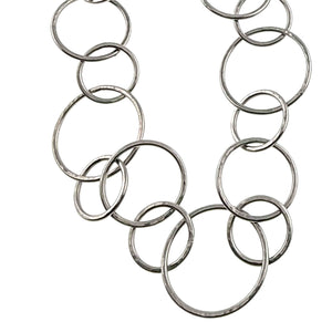 3 of 8: Close view of the hammered stainless steel chain link necklace showing several connected round links in different sizes. The polished silver tone metal reveals the hand hammered surface and slight shape changes that give each link a handmade look.
