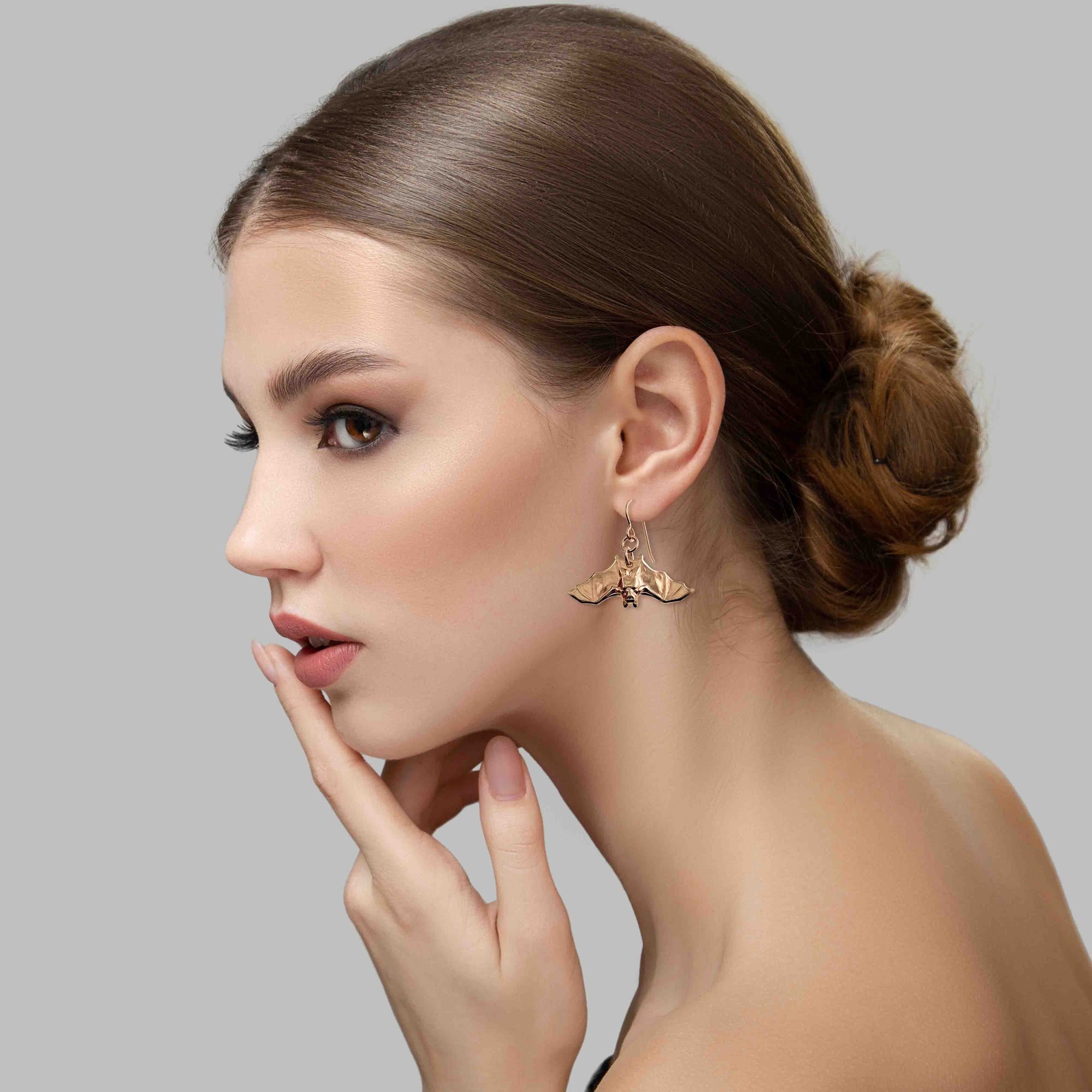 Woman wearing a Hanging Bat Bronze Dangle Earring with a neutral background