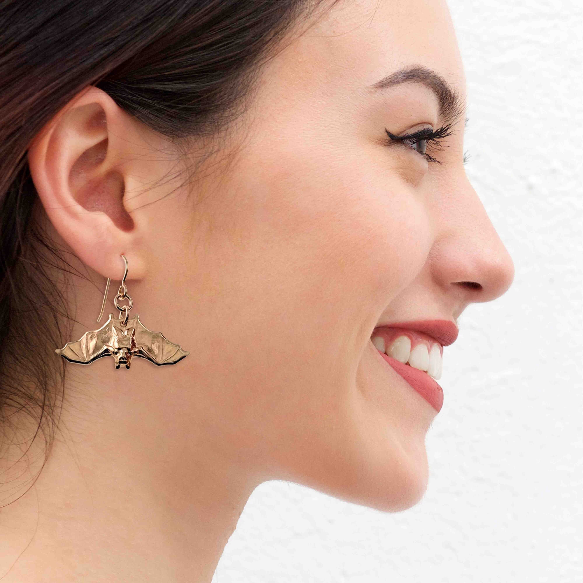Woman wearing a Hanging Bat Bronze Dangle Earring on a white background