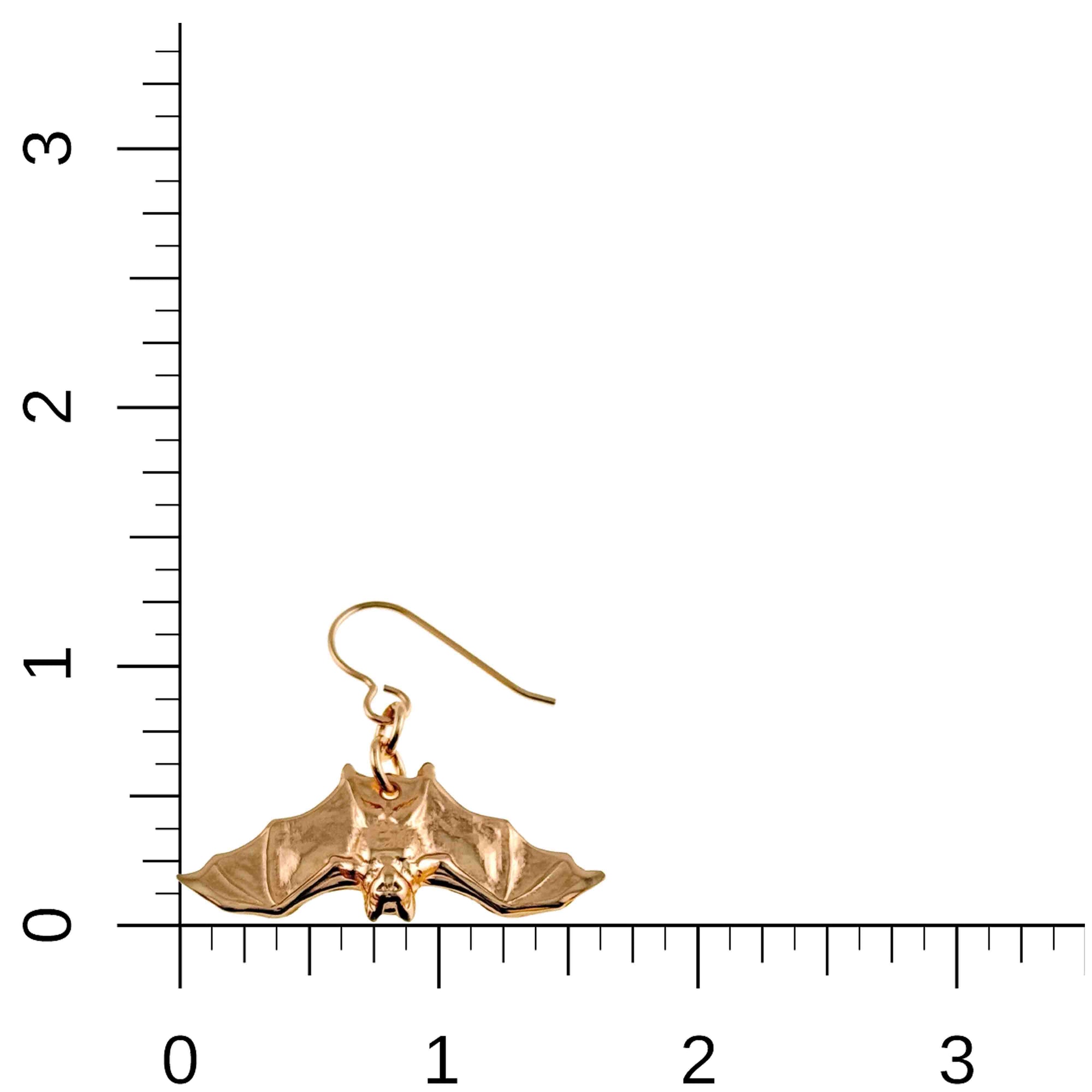 Bronze bat-shaped earring on a ruler for scale