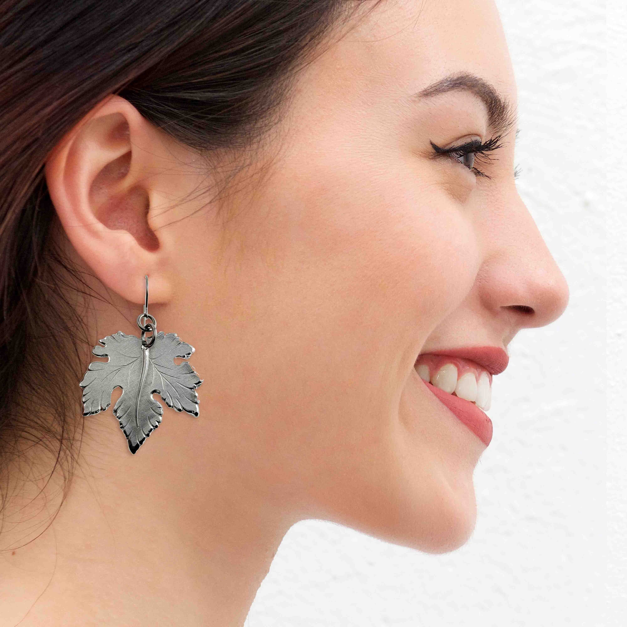 Woman wearing Large Maple Leaf Aluminum Dangle Earrings with a plain background