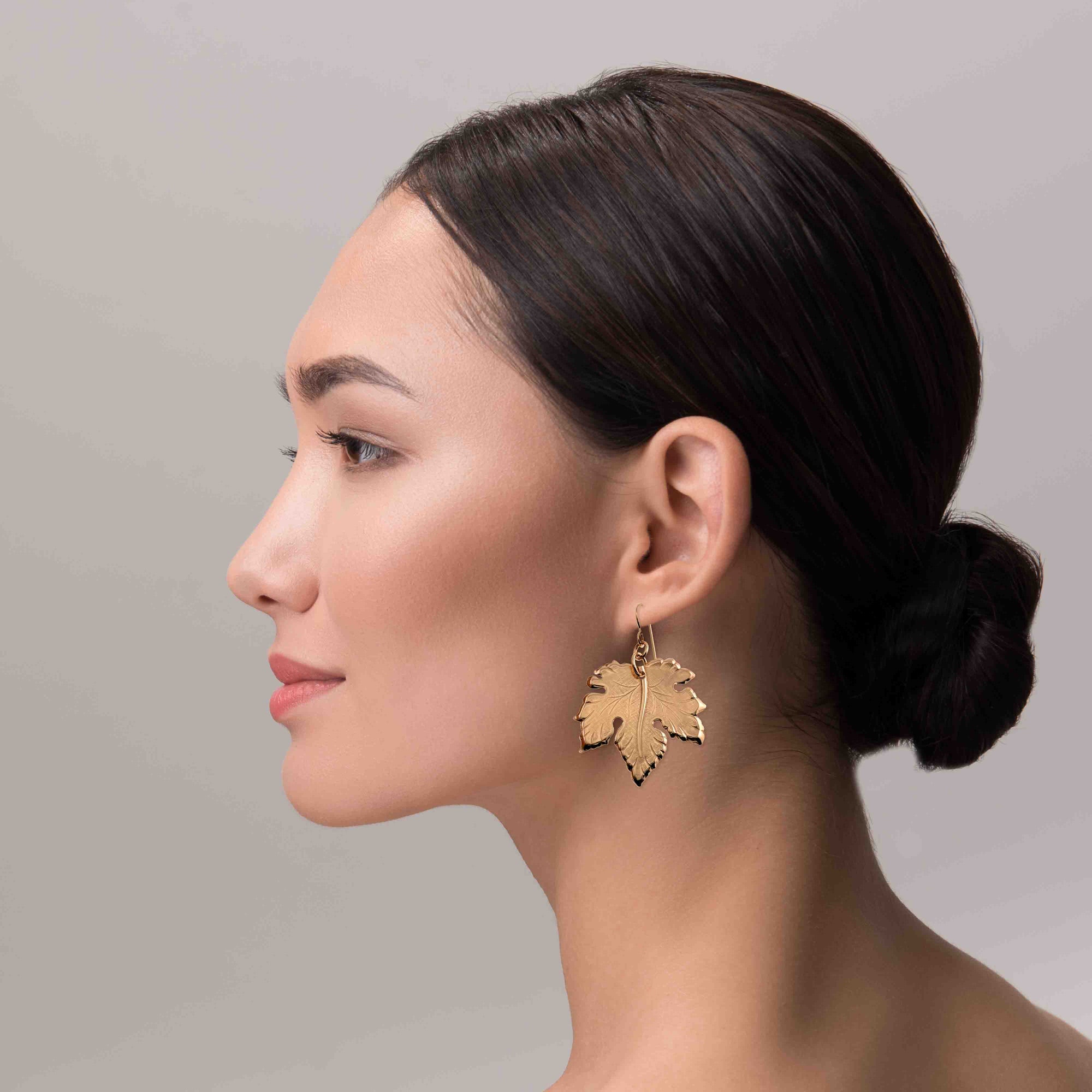 A Sophisticated Woman Wearing Large Maple Leaf Bronze Dangle Earrings